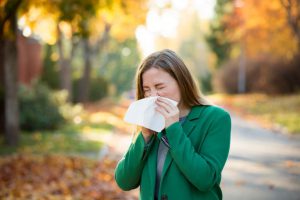 mulher assoando o nariz com alergias no outono