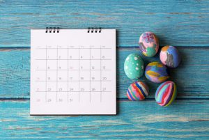 um calendário ao lado de vários ovos coloridos para a Páscoa
