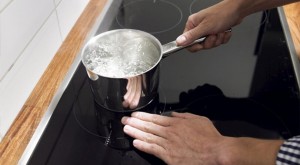 Imagem com pessoa fervendo água em fogão Cooktop