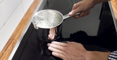 Imagem com pessoa fervendo água em fogão Cooktop