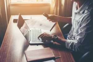 Profissional em escritório usando notebook e smartphone