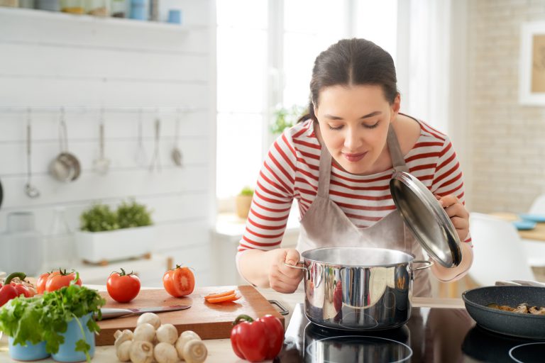 Imagem mostra uma mulher preparando comida usando seu cooktop de indução