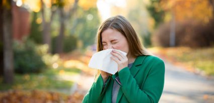 mulher assoando o nariz com alergias no outono