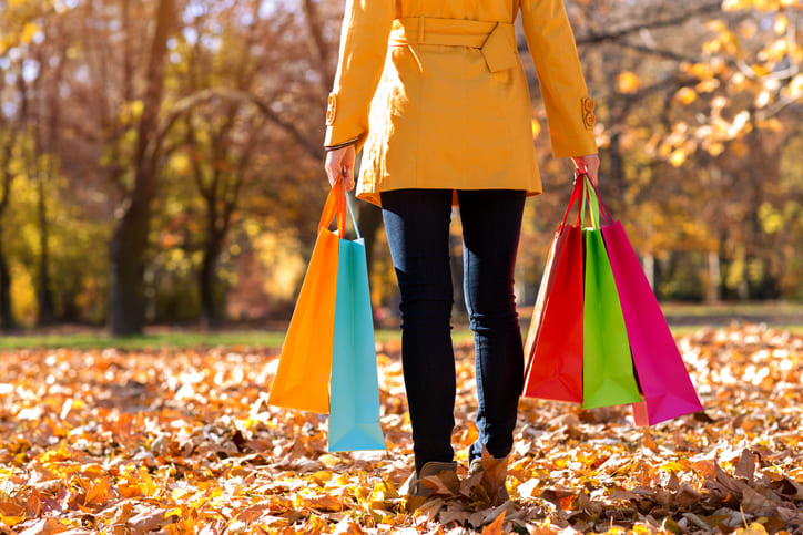 mulher com roupas de frio segurando sacolas de compras coloridas no Outono