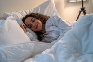 mulher deitada em cama confortável dormindo feliz