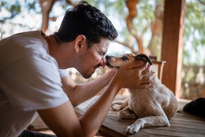 homem encosta seu nariz no do cachorro branco