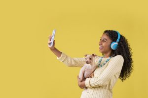 mulher com cachorro no colo tira foto com o smartphone